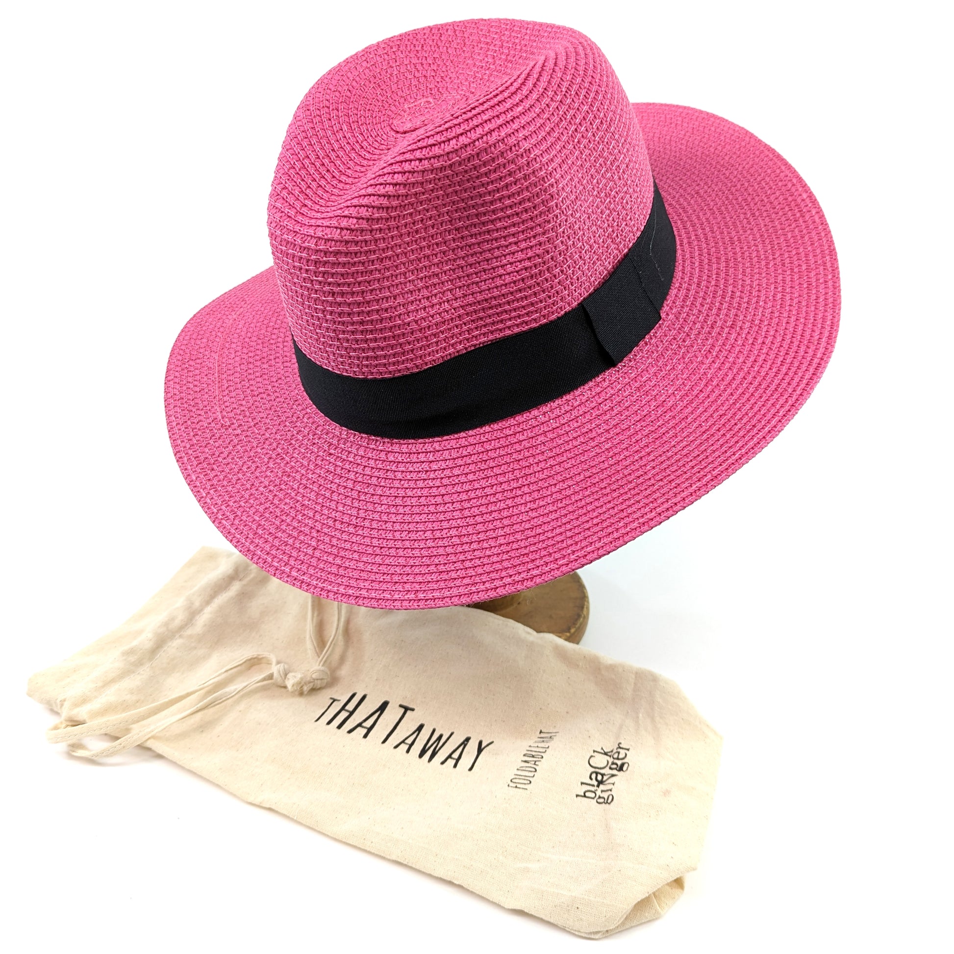 Image shows a bright pink panama hat with a black ribbon around the centre