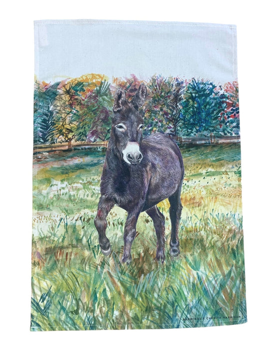Image shows a beautiful illustration of our brown donkey called Denver standing in a field with a mixture of shades of green trees in the background printed onto a cotton tea towel