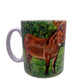 Image shows a white handled mug with a beautifully drawn image of our brown mule muffin standing in a grassy field with a line of autumnal colour trees which wraps around the mug