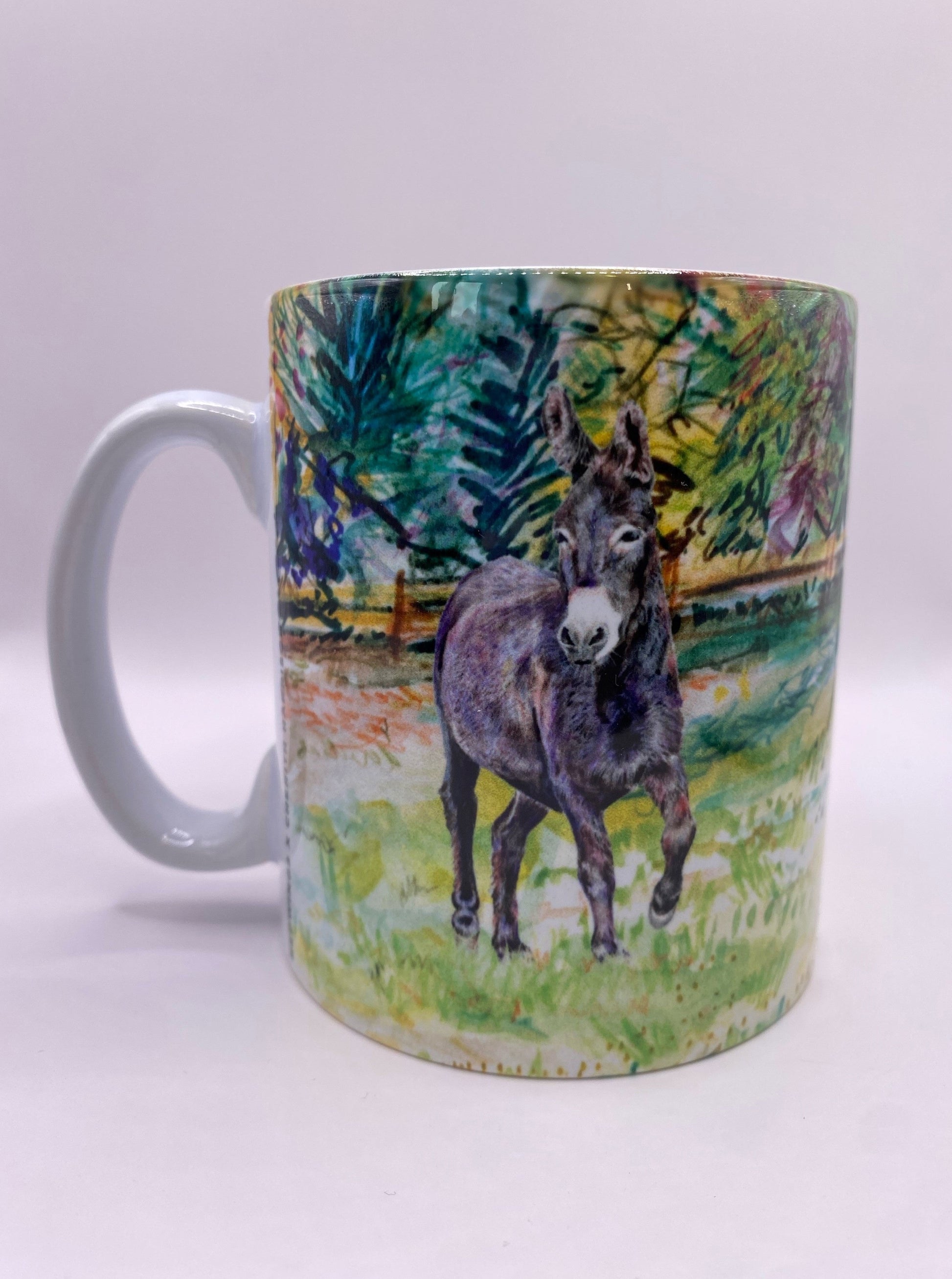 Image shows a beautiful illustration of our brown donkey called Denver standing in a field with a mixture of shades of green trees in the background. Image wraps around the mug