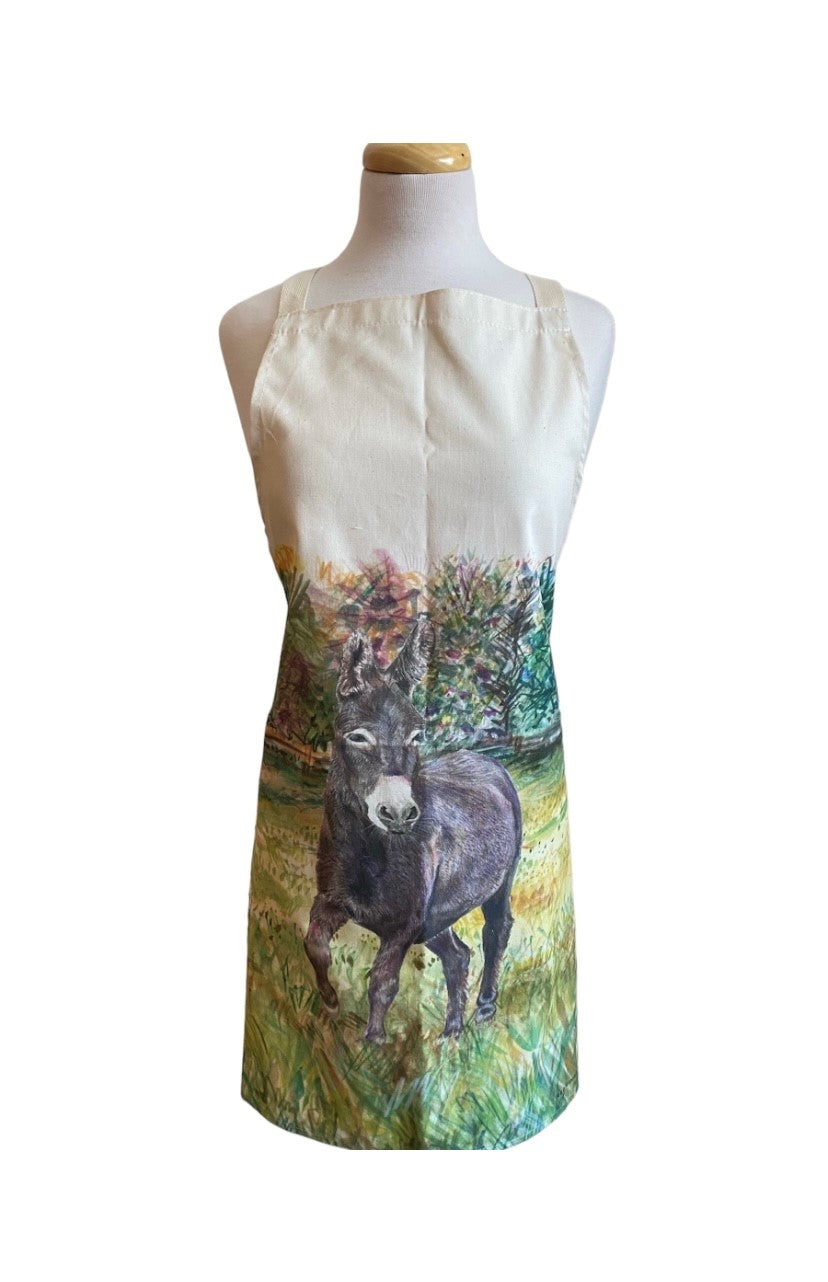 Image shows a cream cotton apron with a beautifully drawn image of our brown Denver the donkey standing in a grassy field