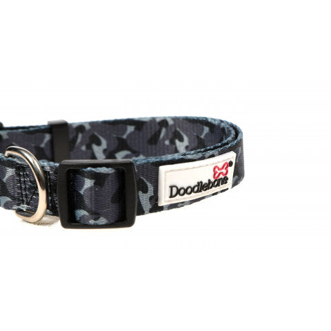 Image shows a black and grey camo print dog collar with black hearwear and a white doodlebone logo