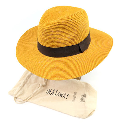 Image shows a mustard yellow panama hat with a black ribbon around the centre